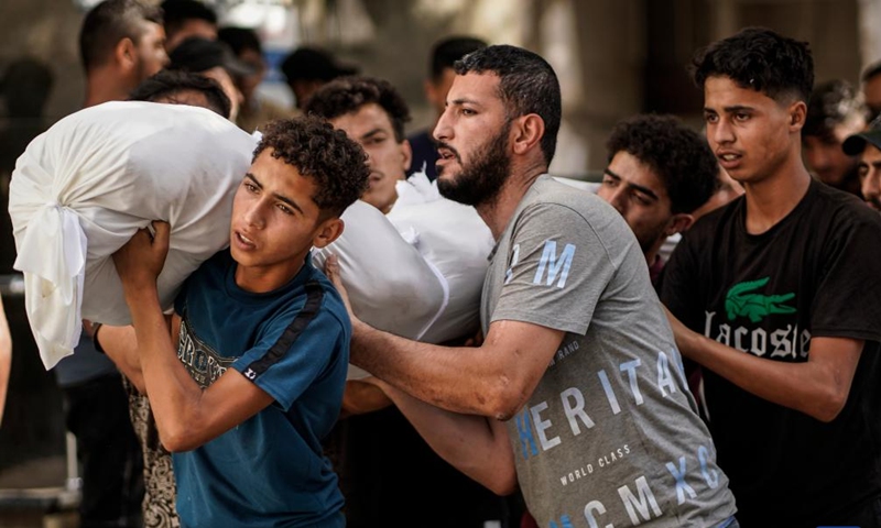 Palestinians carry the body of a victim killed in an Israeli airstrike, at Al-Shifa hospital in Gaza City, on June 14, 2026. (Photo by Rizek Abdeljawad/Xinhua)