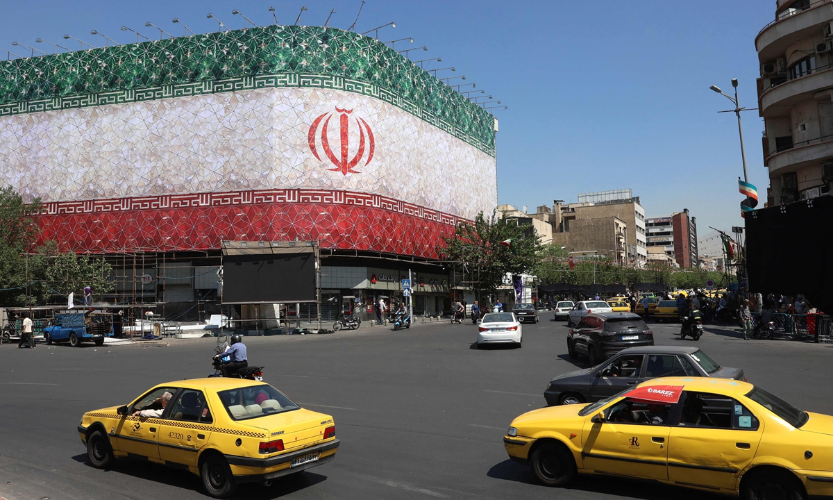 : Vehicles drive past a building flying the Iranian flag at Enghelab Square in Tehran, Iran, on June 14, 2026. Photo: VCG



