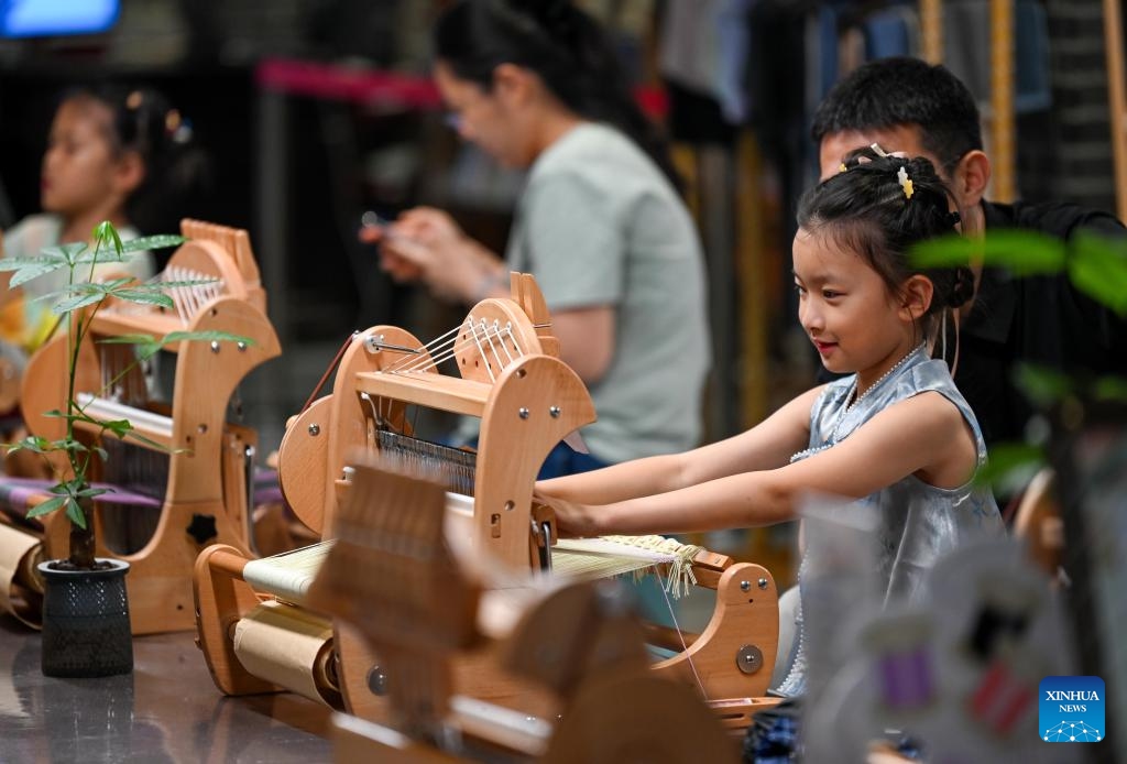 A child experiences textile-making techniques at a cultural and art park, transformed from the former cotton textile factories, in Shijiazhuang City, north China's Hebei Province, June 13, 2026. In recent years, Shijiazhuang has advanced the protection and utilization of industrial heritage, injecting new vitality to the city's development. A number of old factory buildings and former industrial sites have been transformed into urban cultural landmarks, leisure and sports parks, creative markets and other new spaces. (Photo: Xinhua)
