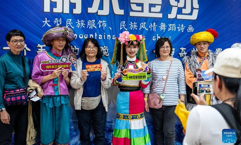 Members of the audience pose for a photo with actors before the Mountains Rivers Show in Lijiang, southwest China's Yunnan Province, June 17, 2026. Since its premiere in Lijiang in May 2002, the show has been a long-running hit in 24 years, staging over 21,000 times, and has drawn an audience of about 20 million . (Xinhua/Hu Chao)