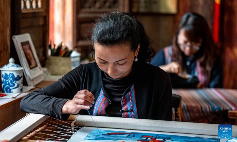 An embroiderer of the Naxi ethnic group makes embroidery work at Baisha ancient town in Lijiang, southwest China's Yunnan Province, June 17, 2026. In recent years, Baisha ancient town has drawn on its historical legacy and rich ethnic cultural resources to advance the preservation, transmission and innovative development of the embroidery of the Naxi ethnic group, injecting new vitality into the ancient craft. Photo: Xinhua