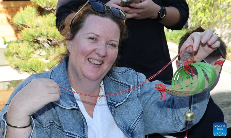 A visitor displays her handmade bamboo-weaving dragon boat during a fair called Tea for Harmony and Dragon Boat Festival Cultural Fair in Sydney held at a park in Sydney, Australia, June 20, 2026. Photo: Xinhua