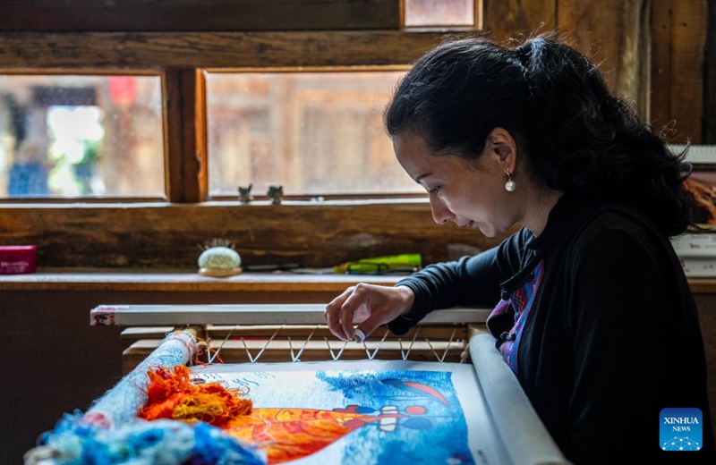 An embroiderer of the Naxi ethnic group makes embroidery work at Baisha ancient town in Lijiang, southwest China's Yunnan Province, June 17, 2026. In recent years, Baisha ancient town has drawn on its historical legacy and rich ethnic cultural resources to advance the preservation, transmission and innovative development of the embroidery of the Naxi ethnic group, injecting new vitality into the ancient craft. Photo: Xinhua