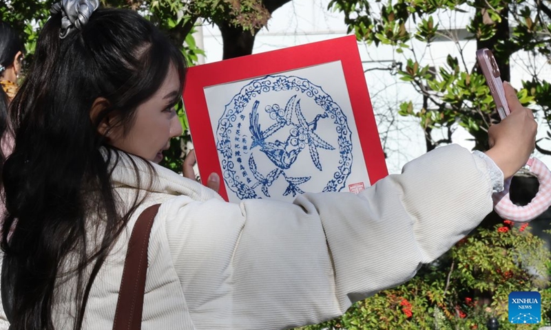 A visitor takes a selfie with her handmade Yangliuqing woodblock painting during a fair called Tea for Harmony and Dragon Boat Festival Cultural Fair in Sydney held at a park in Sydney, Australia, June 20, 2026. Photo: Xinhua