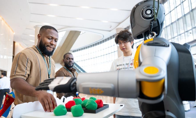 A representative interacts with a robot before the opening ceremony of the 2026 World Youth Development Forum in Wuhan, central China's Hubei Province, June 15, 2026. (Xinhua/Wu Zhizun)
