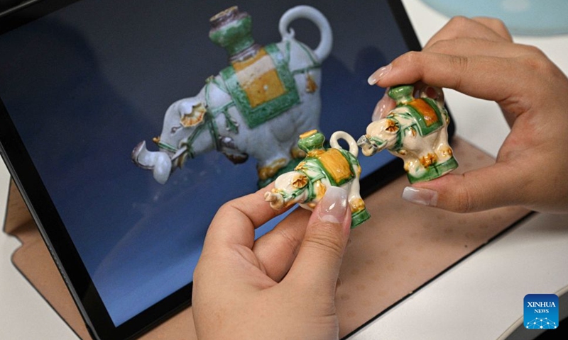 A staff member compares the details of creative products with cultural relics at the China (Hainan) Museum of The South China Sea in Qionghai, south China's Hainan Province, July 2, 2026.
