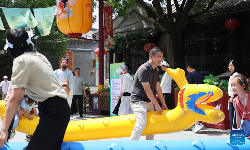 Touritsts participate in a game of dragon boat on the ground at Yangliuqing ancient town in Tianjin, north China, June 21, 2026. People enjoyed the three-day holiday of the Dragon Boat Festival, also called Duanwu Festival, which falls on June 19 this year, via various activities across the country. (Xinhua/Li Ran)
