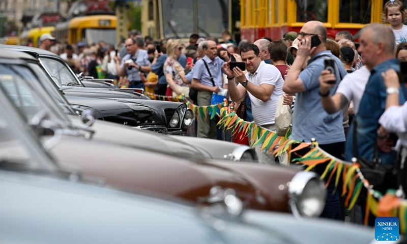 A man takes photos of retro cars during a vintage vehicle exhibition in Moscow, Russia, July 11, 2026. A retro tram parade and a vintage vehicle exhibition were held on Saturday to celebrate the Moscow Transport Day, which falls on the second Saturday of July each year. (Photo by Alexander Zemlianichenko Jr/Xinhua)