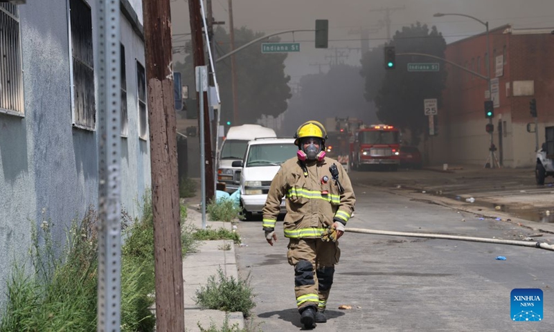 A firefighter works at a facility where a fire has erupted in Boyle Heights, Los Angeles, California of the United States, on June 20, 2026. Mayor Karen Bass of the U.S. city of Los Angeles on Saturday declared a local emergency in response to an ongoing warehouse fire that erupted Wednesday and generated heavy smoke, which has spread across the Los Angeles metropolitan area for several days. (Photo by Zeng Hui/Xinhua)

