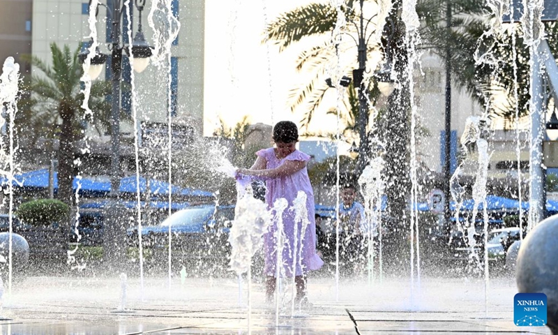 A girl plays in a fountain to cool off at the old market in Kuwait City, Kuwait, July 11, 2026. (Photo by Asad/Xinhua)

