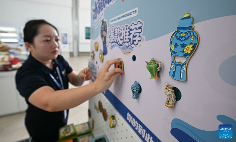 A staff member displays creative products inspired by discoveries of shipwrecks on the northwest continental slope of the South China Sea at the China (Hainan) Museum of The South China Sea in Qionghai, south China's Hainan Province, July 1, 2026.