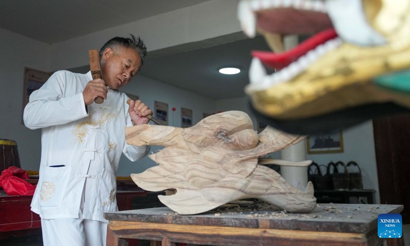 Xu Guisheng carves a dragon head at a workshop in Miluo City, central China's Hunan Province, June 9, 2026. Over 60 years old, Xu is the representative inheritor of the Miluo dragon boat making technique, a Hunan provincial intangible cultural heritage item. The craft has been passed down through five generations in his family, with Xu as the fifth-generation inheritor. (Xinhua/Xue Yuge)

