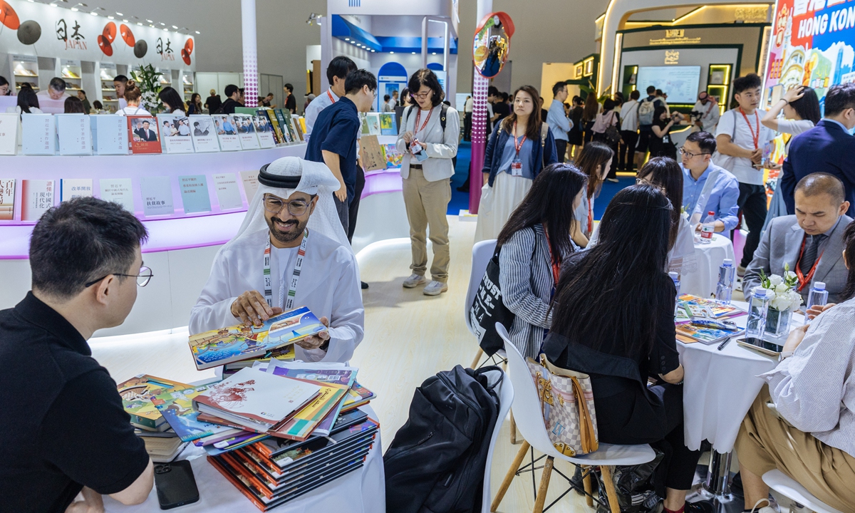 A UAE participant  and a Chinese attendee exchange views at the book fair on June 17, 2026.
