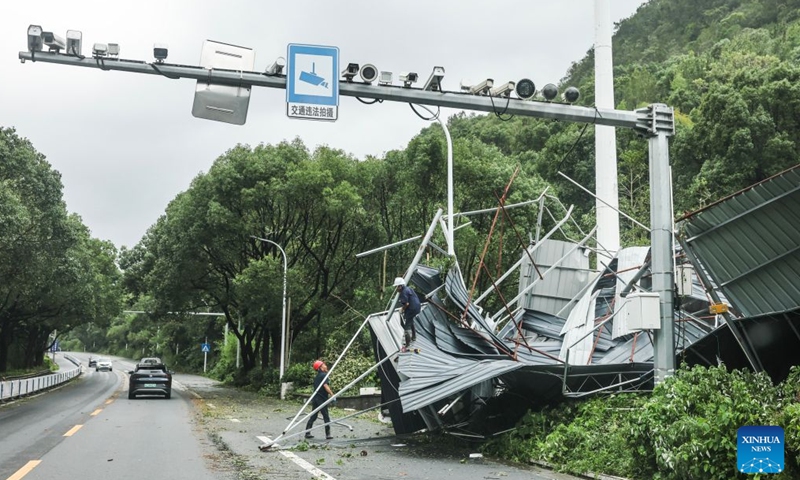 Workers clear a destroyed building blown down by strong winds beside a highway from Wenling to Yuhuan in east China's Zhejiang Province, July 12, 2026.