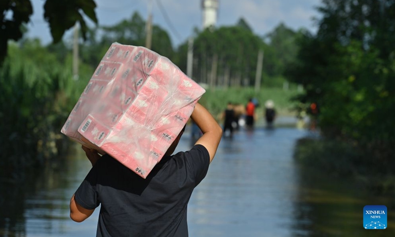 A volunteer transports supplies in Guigang, south China's Guangxi Zhuang Autonomous Region, July 10, 2026. Triggered by Typhoon Maysak, the tenth typhoon of the year, heavy downpours battered multiple areas in south China's Guangxi Zhuang Autonomous Region, resulting in a series of disasters. Various response forces have pooled their efforts, carrying out operations including rescue missions in remote mountainous areas, restoration of transport and power infrastructure, and silt clearing operations. (Xinhua/Zhou Hua)
