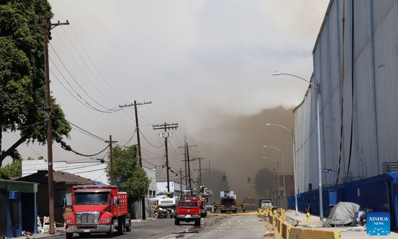 Firefighters work at a facility where a fire has erupted in Boyle Heights, Los Angeles, California of the United States, on June 20, 2026. Mayor Karen Bass of the U.S. city of Los Angeles on Saturday declared a local emergency in response to an ongoing warehouse fire that erupted Wednesday and generated heavy smoke, which has spread across the Los Angeles metropolitan area for several days. (Photo by Zeng Hui/Xinhua)

