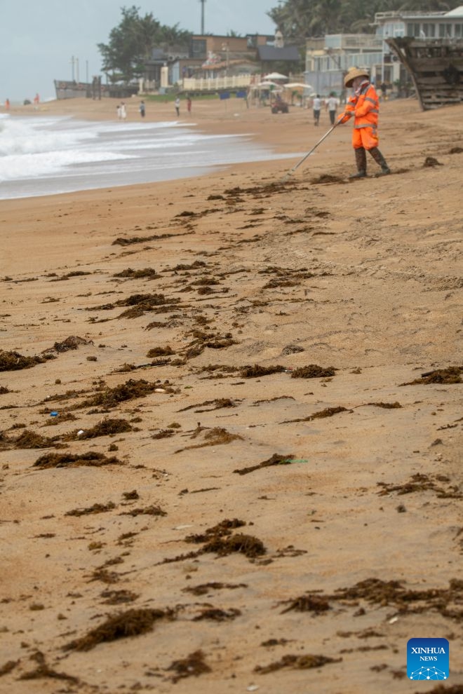 A sanitation worker collects debris and garbage washed ashore during a tropical storm landfall on a beach in Boao of Qionghai City, south China's Hainan Province, July 4, 2026. The tropical storm came ashore at around 6:20 p.m. in Yelin Township of Lingshui Li Autonomous County, according to the Hainan provincial meteorological bureau. At landfall, it packed maximum winds of 23 meters per second near its center. (Photo by Meng Zhongde/Xinhua)