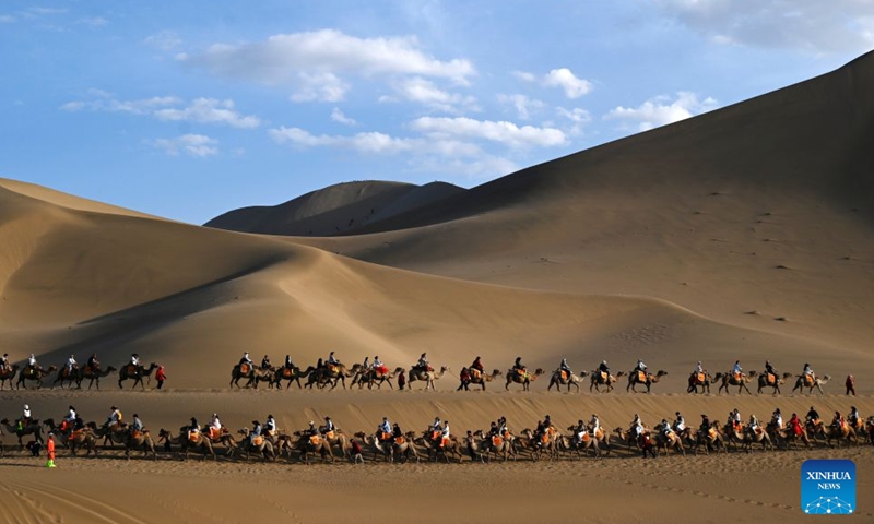 Tourists ride camels at the Mingsha Mountain and Crescent Spring Scenic Area in Dunhuang, northwest China's Gansu Province, June 19, 2026. People enjoyed the three-day holiday of the Dragon Boat Festival, also called Duanwu Festival, which falls on June 19 this year, via various activities across the country. (Photo by Zhang Xiaoliang/Xinhua)