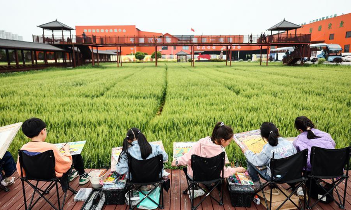 Children draw pictures beside the fields at Yuxin Town of Nanhu District in Jiaxing City, east China's Zhejiang Province, April 27, 2024. (Xinhua/Lan Hongguang)
