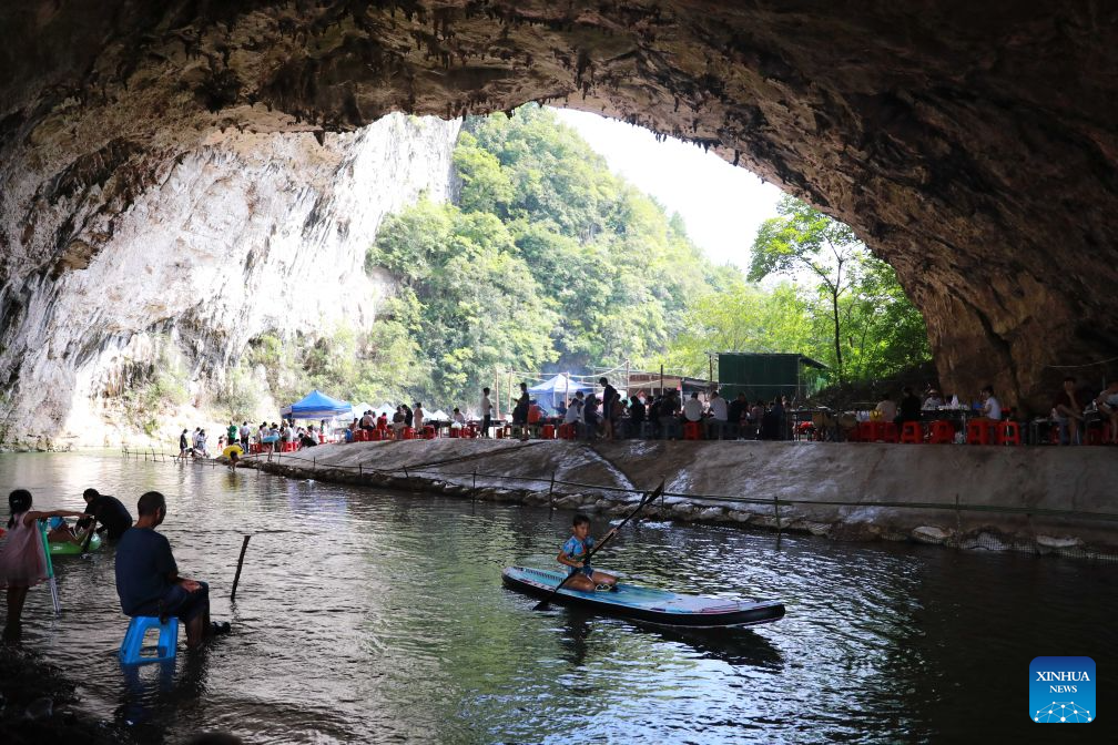 Tourists have fun inside a karst cave in Kaili City, Qiandongnan Miao and Dong Autonomous Prefecture, southwest China's Guizhou Province, Aug. 8, 2026. Best known for its karst landscape, Guizhou has made the best of karst caves to develop distinctive sites for cooling retreats. Featuring natural geological wonders, cooling enjoyment and water amusements, this emerging tourist experience has become a hit among locals and visitors alike. (Photo by Wu Xianyan/Xinhua)