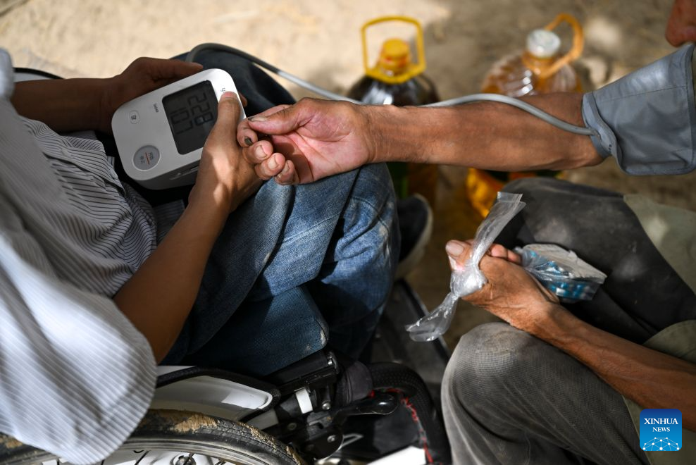Li Chuangye (L) measures blood pressure for a senior in Bexkant Town, Shache County of northwest China's Xinjiang Uygur Autonomous Region, July 27, 2026. (Xinhua/Hu Huhu)