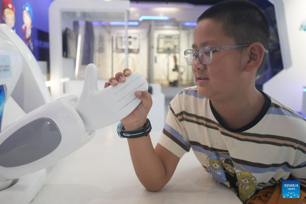 A child competes with a robot in a hand wrestling game at a science and technology museum in Zunyi, southwest China's Guizhou Province, Oct. 6, 2026. Advanced technologies such as exoskeleton devices, AI-powered glasses and robots have enabled diverse and dazzling experiences at tourist destinations across China during the National Day holiday. (Photo by Zhang Zhengju/Xinhua)