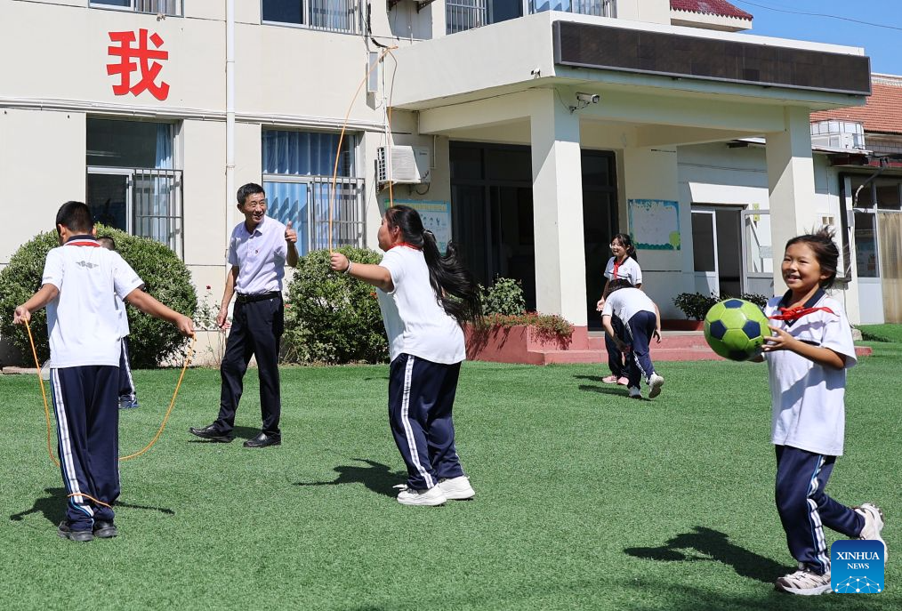 Zheng Baoguo thumbs up to encourage students on the school playground in Luozhuangzi Town of Jizhou District in Tianjin, north China, on Sept. 3, 2026. (Xinhua/Li Ran)