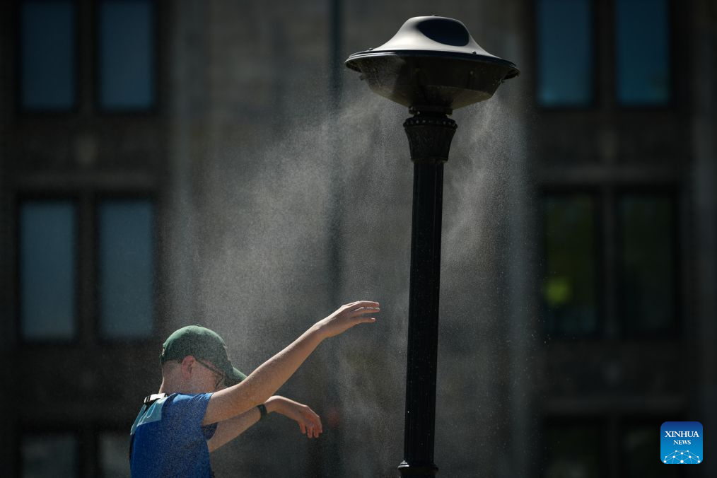 A boy reaches out to a mist shower to cool off in Warsaw, Poland, July 16, 2026. (Photo by Jaap Arriens/Xinhua)