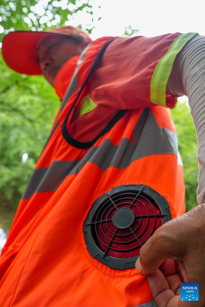A sanitation worker presents a cooling vest in Nanjing, east China's Jiangsu Province, July 28, 2026. Recently, in response to the high summer temperatures, sanitation workers in Xuanwu District of Nanjing City have been equipped with cooling vests. The vests are fitted with miniature fans on both sides of the waist, providing inward airflow. (Xinhua/Li Bo)