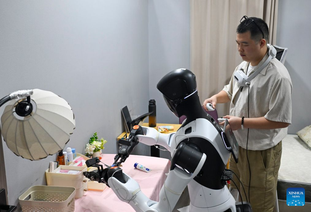 A staff member trains a robot to do chores at Maniformer, a physical AI data service platform, in Shanghai, east China, Aug. 5, 2026. In Shanghai's tech companies like AGIBOT and Maniformer, embodied intelligence robots are trained in household, retail, sorting, production and other real-world scenarios, to advance their AI capabilities for real-life use. (Xinhua/Liu Ying)
