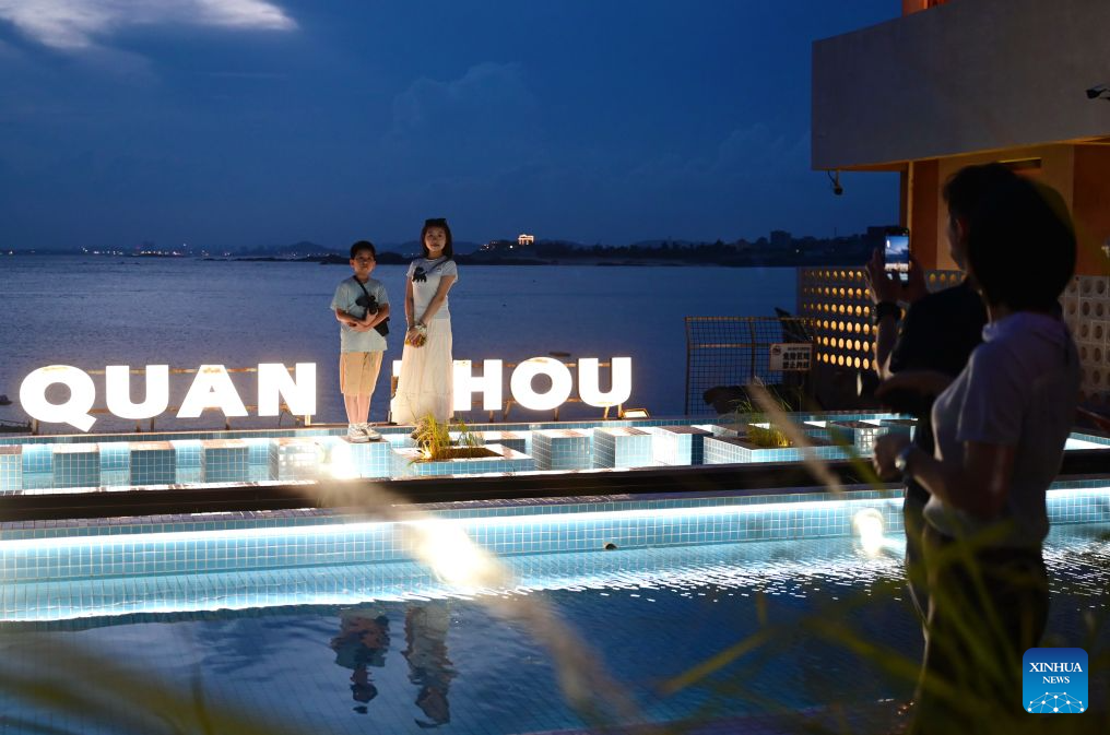 People pose for photos at the Chongwu ancient ferry terminal scenic area in Hui'an County of Quanzhou, southeast China's Fujian Province, Aug. 17, 2026. The Chongwu ancient ferry terminal covers an area of 33 mu (about 2.2 hectares) in Hui'an County of southeast China's Fujian Province. In 2024, local authorities transformed it from an idle terminal into a coastal vacation destination that integrates art galleries, a pier runway, trendy restaurants, and family playgrounds. (Xinhua/Lin Shanchuan)