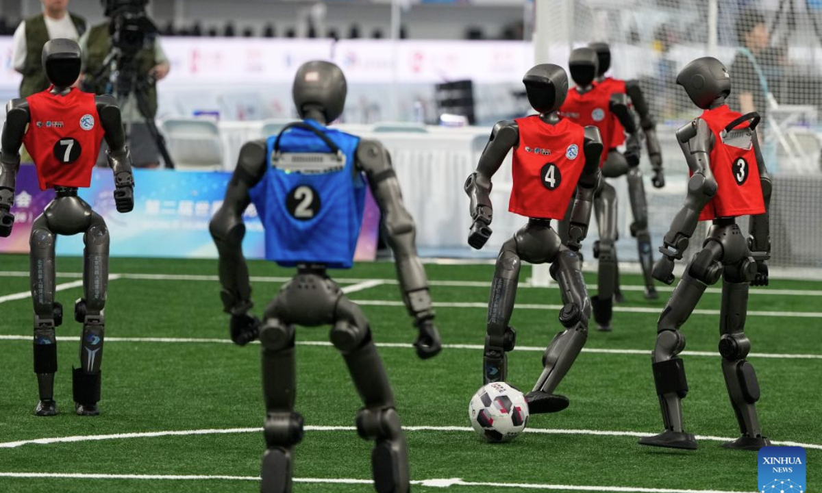 The robot (2nd R) of Tsinghua Vulcan Team competes during the football 5v5 - Large Robot Group match of the 2nd World Humanoid Robot Games in Beijing, capital of China, Aug. 25, 2026. (Xinhua/Ju Huanzong)