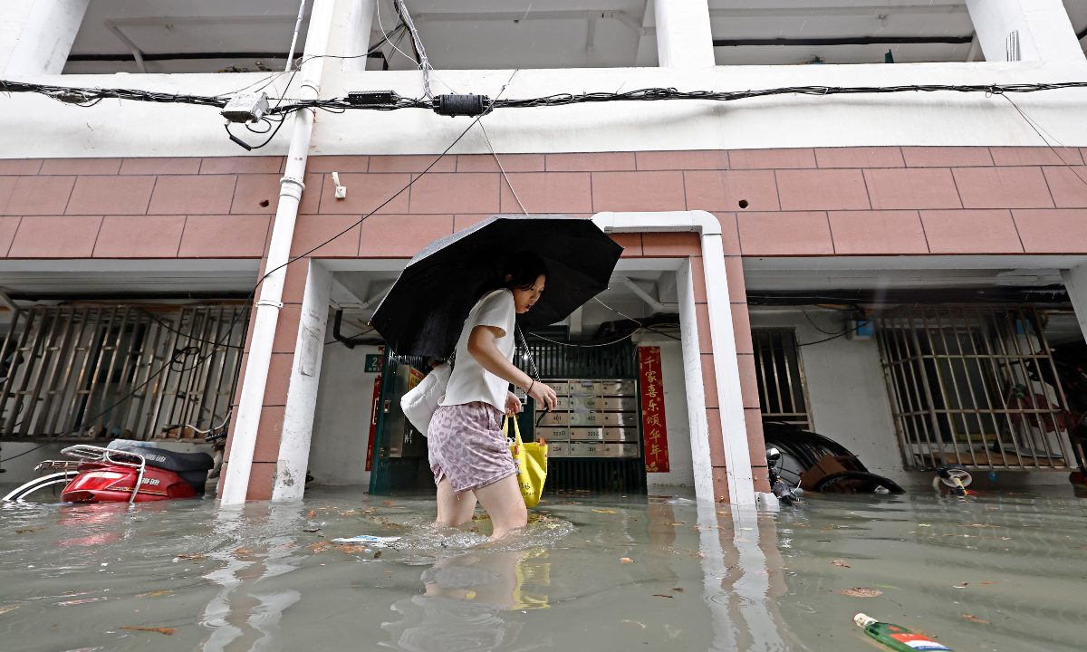 A resident wades through floodwaters in a residential compound in Changning district after heavy rain from Typhoon Dolphin drenched Shanghai on August 9, 2026. Photo: IC