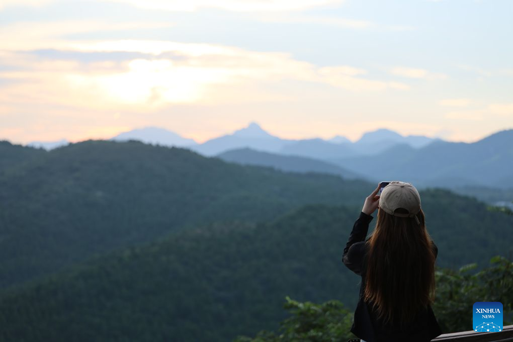 A visitor takes photos of the sunset glow in Xijingyu Village, Jizhou District of north China's Tianjin Municipality, Aug. 4, 2026. During summer vacation, Xijingyu Village has attracted lots of visitors. Known as the Stone Village, it is famous for its distinctive houses and alleys built of stones. (Xinhua/Li Ran)