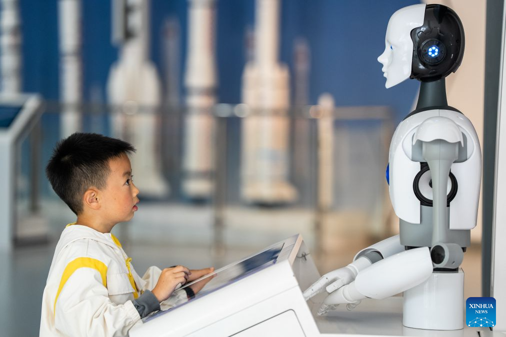 A child interacts with a robot at a science and technology museum in Bijie, southwest China's Guizhou Province, Oct. 6, 2026. Advanced technologies such as exoskeleton devices, AI-powered glasses and robots have enabled diverse and dazzling experiences at tourist destinations across China during the National Day holiday. (Photo by Luo Dafu/Xinhua)