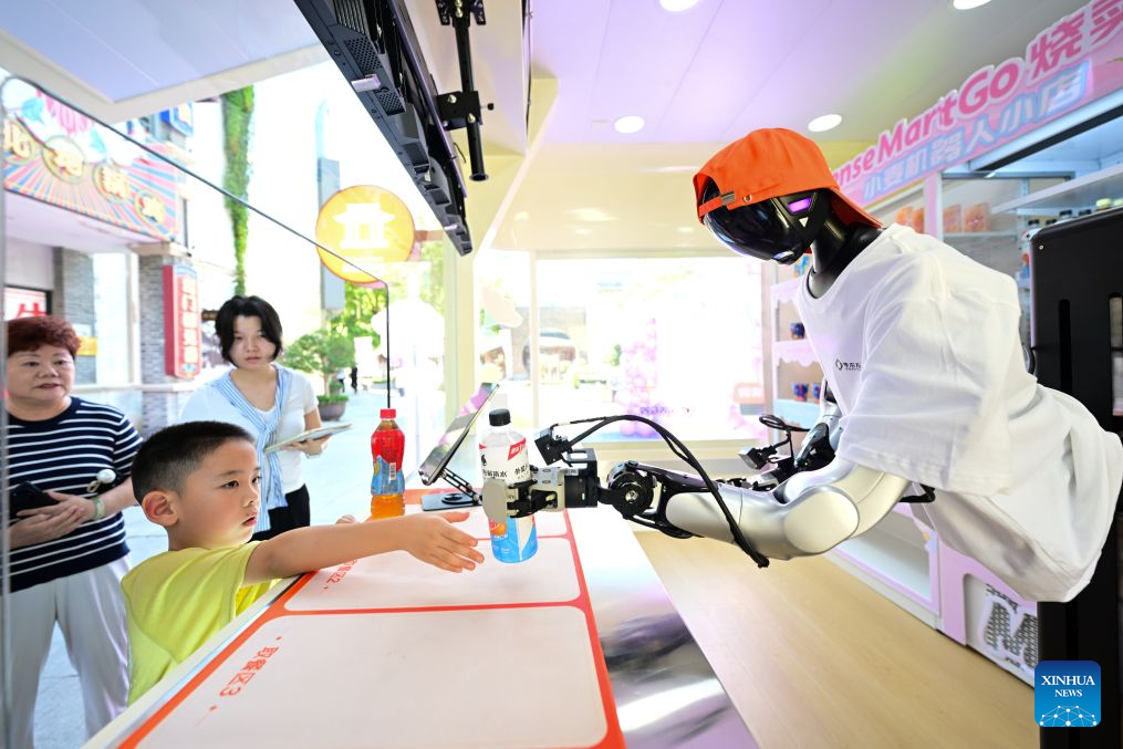 A robot grabs a bottle of electrolyte water and delivers to a customer at an embodied intelligence robot store at Leijie Street in Hefei, east China's Anhui Province, Aug. 26, 2026. Four embodied intelligence robot stores equipped with wheeled humanoid robot shop assistants have officially opened in several cultural, tourism and commercial blocks in Hefei. The robot shop assistants are able to automatically recognize, grab and deliver merchandise to customers. (Xinhua/Zhou Mu)