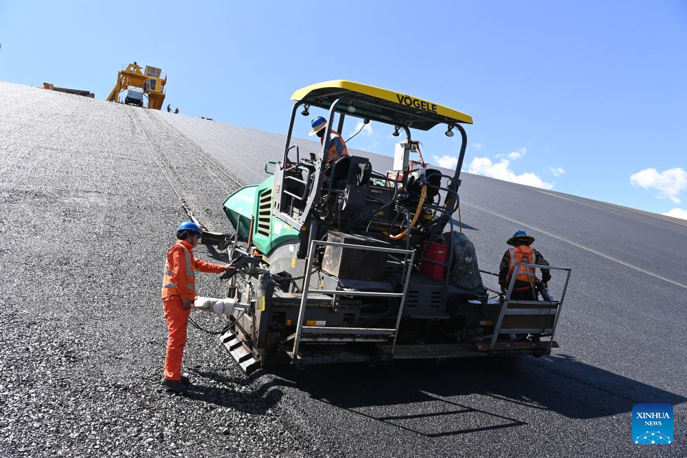 Workers lay asphalt at the construction site of a pumped-storage power station in Zhangye, northwest China's Gansu Province, Aug. 4, 2026. The construction of the power station started in 2022, and all the four 350,000-kW reversible pump-turbine units are expected to be fully put into operation by 2029. (Xinhua/Fan Peishen)