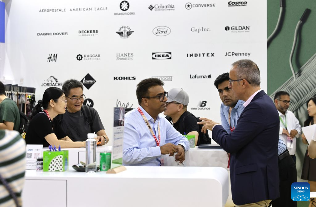 Exhibitors communicate during Intertextile Shanghai Apparel Fabrics - Autumn Edition in east China's Shanghai, Aug. 25, 2026. The trade fair kicked off here on Tuesday. (Xinhua/Fang Zhe)