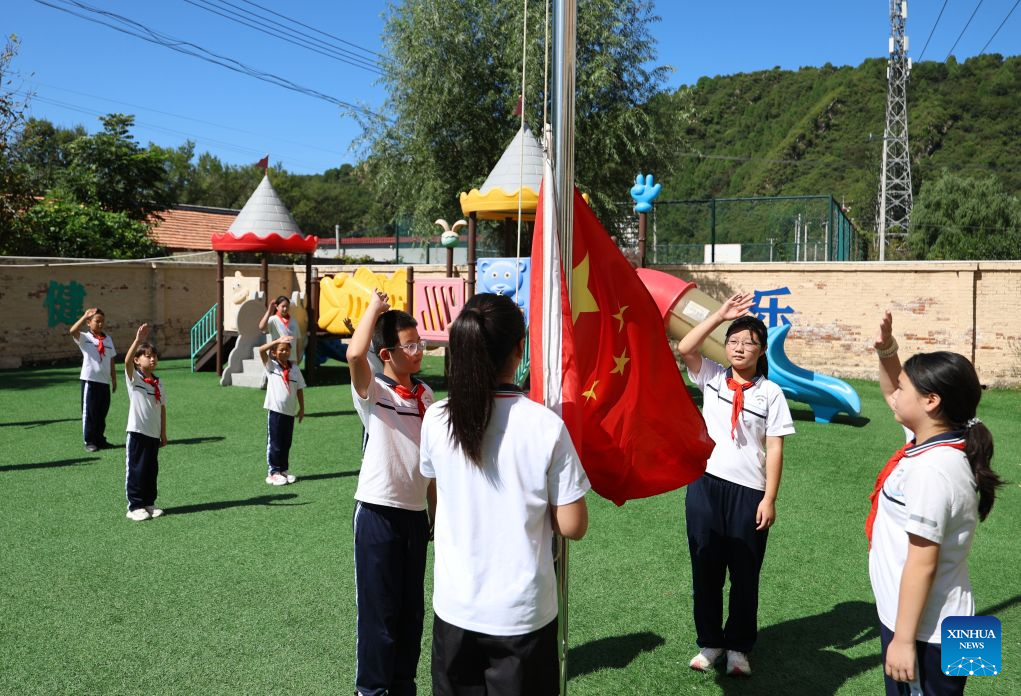Students raise the Chinese national flag on the playground at Hongshuizhuang central primary school Sangyuan branch in Luozhuangzi Town of Tianjin, north China, Sept. 1, 2026. The school, located at the foot of the Yanshan Mountains, has only 28 students from three surrounding villages of Sangyuan, Nihe and Shangbaiyu, and is the primary school with the fewest students in Jizhou District. On the first day of school, it held a flag-raising ceremony and gave the students the first lessons of the new term. (Xinhua/Li Ran)