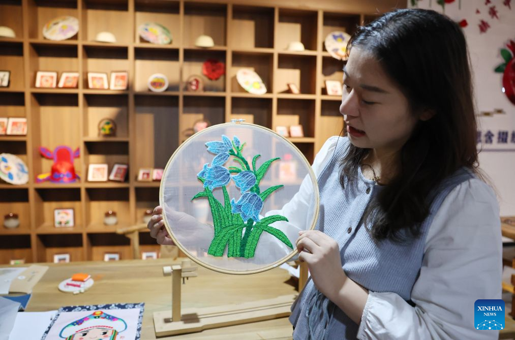 A staff member introduces a Duoxiu embroidery work at a study tour base in Yuanzhou District, Guyuan City of northwest China's Ningxia Hui Autonomous Region, Sept. 21, 2026. Yuanzhou District in Guyuan City has developed an integrated model combining intangible cultural heritage, original design and e-commerce, encouraging local businesses to develop original Duoxiu embroidery patterns and expand handicraft markets. The district has established 12 community handicraft workshops, creating jobs for more than 3,600 people and turning traditional skills into economic opportunities. (Xinhua/Liu Yun)