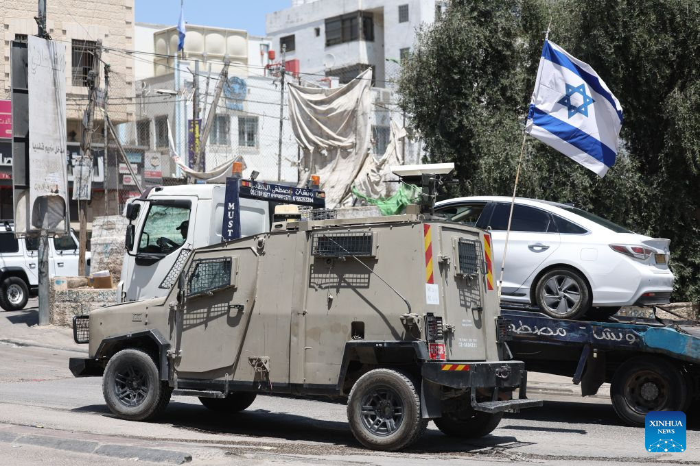 An Israeli military vehicle sets up a roadblock by the roadside near the Qalandiya checkpoint, north of Jerusalem, Aug. 6, 2026. Israeli military and police forces have intensified security operations in and around Jerusalem, as persistent violence across the West Bank drives up regional tensions recently. (Photo by Jamal Awad/Xinhua)