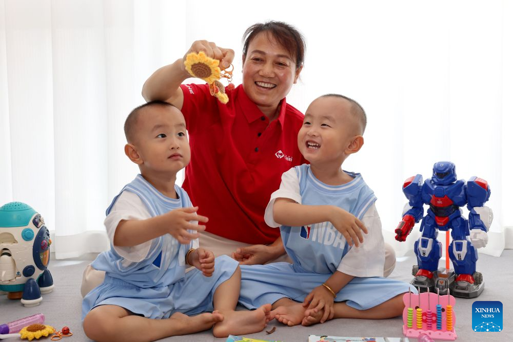 A babysitter takes care of twins at a household in Zaozhuang City, east China's Shandong Province, July 21, 2026. A number of domestic services brands have emerged in Shandong in recent years, offering widely ranging services such as eldercare, maternity care, and in-home caregiving. (Photo by Sun Zhongzhe/Xinhua)