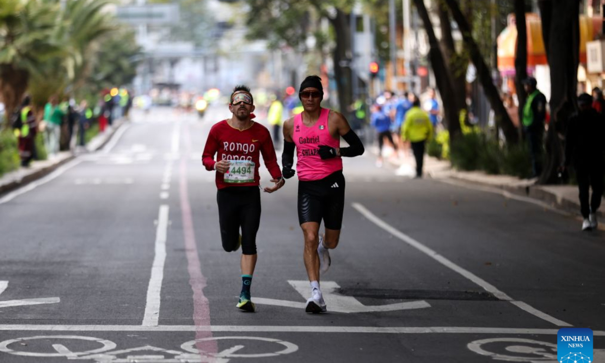 A visually impaired runner (L) participates in the 43rd edition of the Mexico City Marathon in Mexico City, capital of Mexico, on Aug. 30, 2026. (Photo by Francisco Canedo/Xinhua)