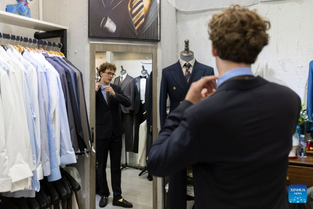 Valentin Gasse, a tourist from Germany, tries on his tailored suit at a clothing store in Shanghai, east China, July 22, 2026. The foreign visitors entering Shanghai increased 22 percent year on year in the first half of 2026, thanks to the country's expanding visa exemption policies. Chinese designer products have emerged as a new driver of inbound consumption. Rather than buying only traditional Chinese specialties such as tea and silk, overseas visitors are increasingly following shopping tips on social media to seek out bags, footwear, clothing and other products by Chinese designers. (Xinhua/Wang Xiang)