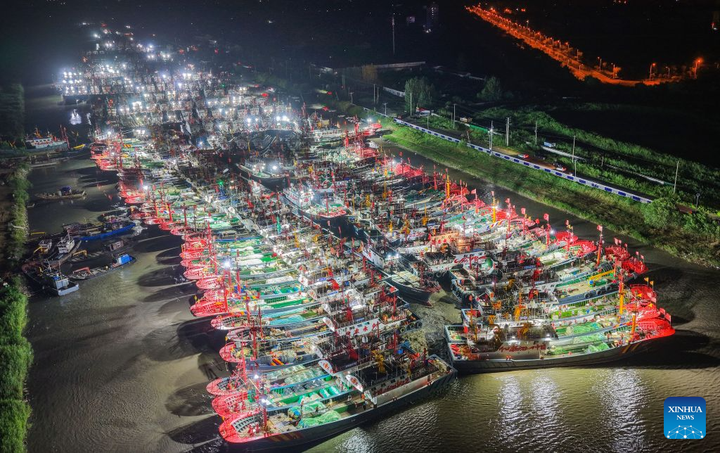 An aerial drone photo taken on Aug. 12, 2026 shows fishing boats preparing to depart for the Yellow Sea after a fishing ban was lifted in Lianyungang City, east China's Jiangsu Province. Special licensed fishing vessels set out to the Yellow Sea as the summer fishing moratorium was partially lifted on Aug. 12, which had been postponed for a week due to impacts of Typhoon Dolphin. (Photo by Wang Jianmin/Xinhua)