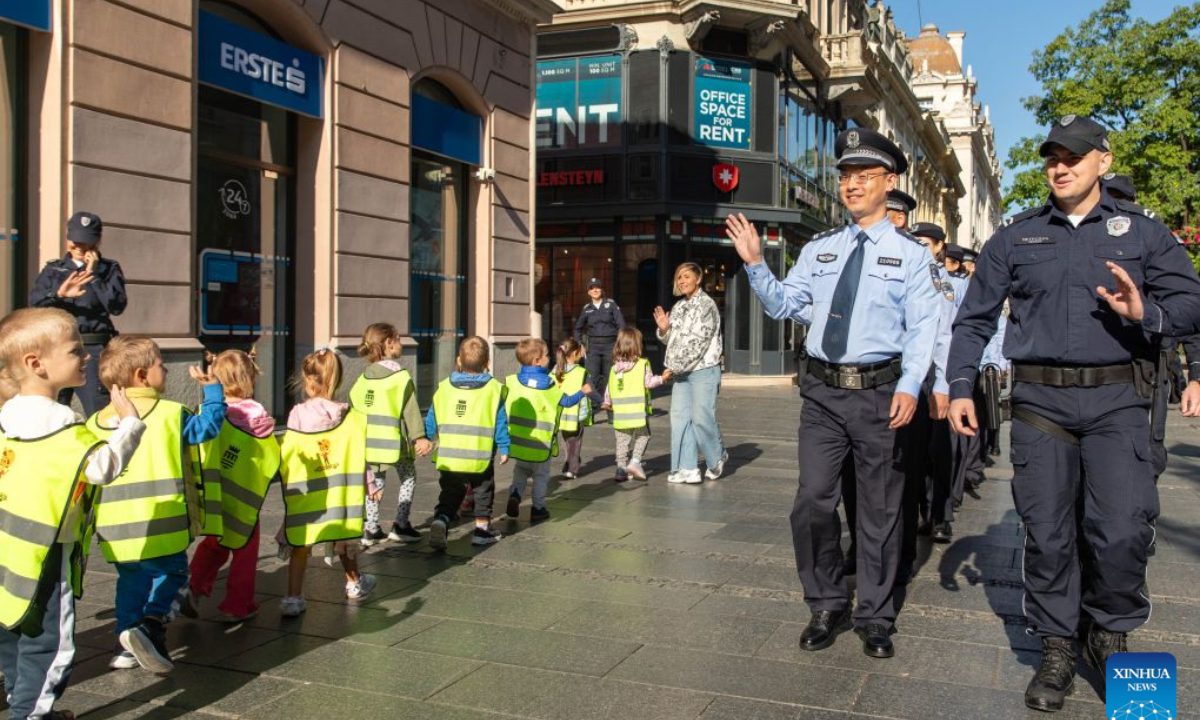 Chinese and Serbian police officers wave to children during a joint patrol on a street in Belgrade, Serbia, Sept. 23, 2026. Chinese and Serbian police officers launched a three-week joint patrol program in downtown Belgrade on Wednesday, aiming at assisting Chinese tourists and residents and strengthening bilateral law enforcement cooperation. (Photo by Wang Wei/Xinhua)
