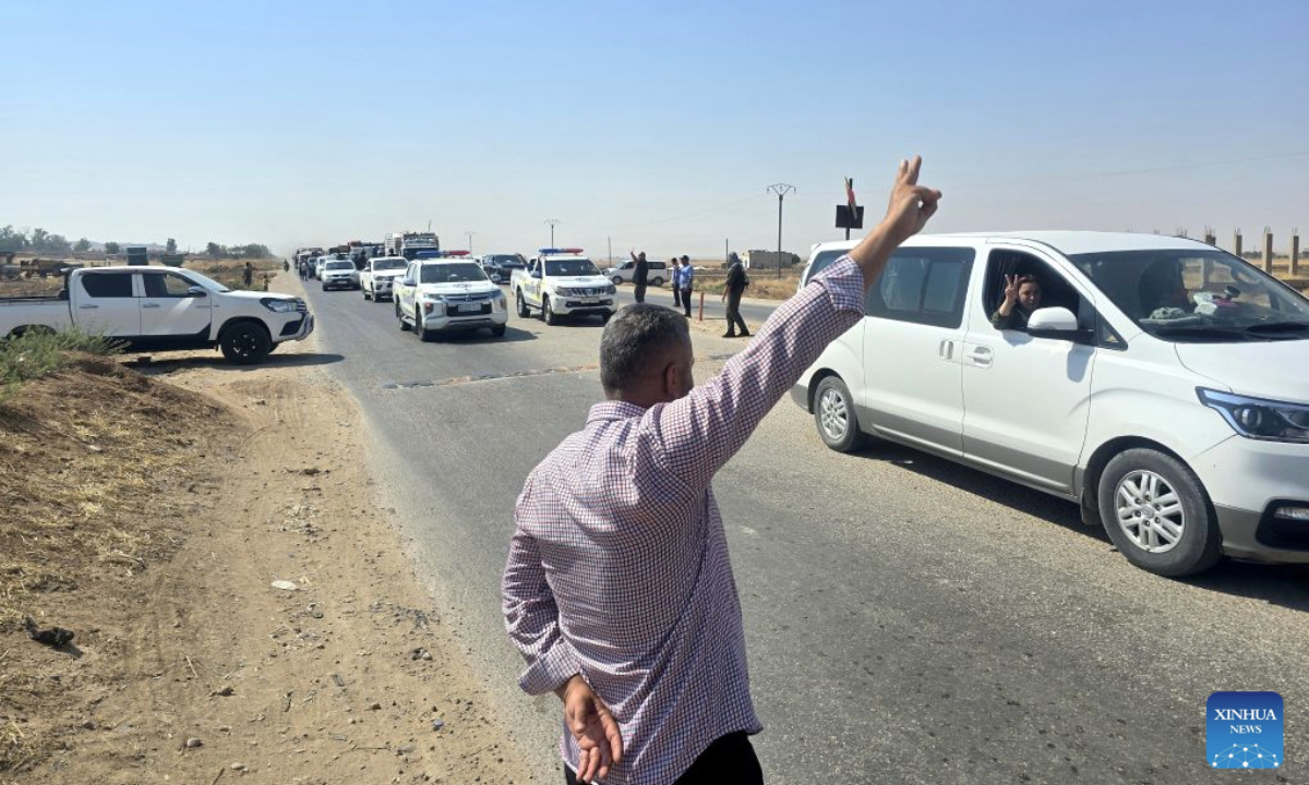 A man waves as a convoy carrying displaced Syrian families heads toward the city of Ras al-Ain and its surrounding villages in Hasakah province, northeastern Syria, Aug. 10, 2026. More than 400 Syrian families returned to the city of Ras al-Ain in northeastern Hasakah province and its surrounding villages on Monday, marking the first organized convoy of displaced residents heading home in that area after nearly seven years of displacement. (Str/Xinhua)