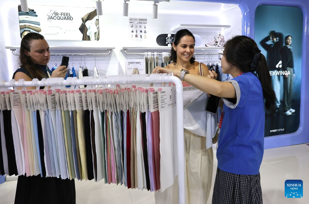 A staff member (R) communicates with a visitor during Intertextile Shanghai Apparel Fabrics - Autumn Edition in east China's Shanghai, Aug. 25, 2026. The trade fair kicked off here on Tuesday. (Xinhua/Fang Zhe)