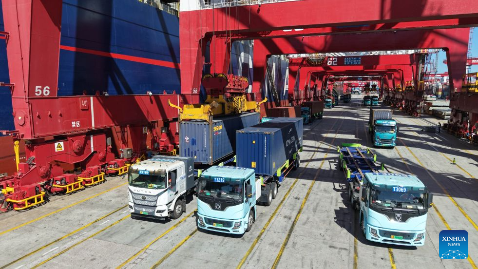 A drone photo taken on Oct. 8, 2026 shows freight trucks at a container terminal of Qingdao Port in Qingdao, east China's Shandong Province. As an international shipping hub in Northeast Asia, Qingdao Port has been expanding its shipping network, adding 16 foreign trade routes so far this year. The port now operates nearly 240 foreign trade routes, connecting over 700 ports in over 180 countries and regions. (Xinhua/Li Ziheng)