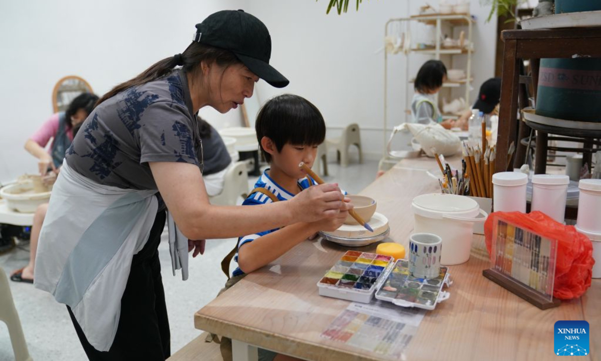 A child engages in a hands-on porcelain-painting experience in Jingdezhen, east China's Jiangxi Province, July 1, 2026. Featuring various museums, hands-on porcelain-making experiences, diverse ceramic art installations, and a slow-paced lifestyle, Jingdezhen has become a trendy destination for young tourists during the summer vacation. (Xinhua/Zhou Mi)
